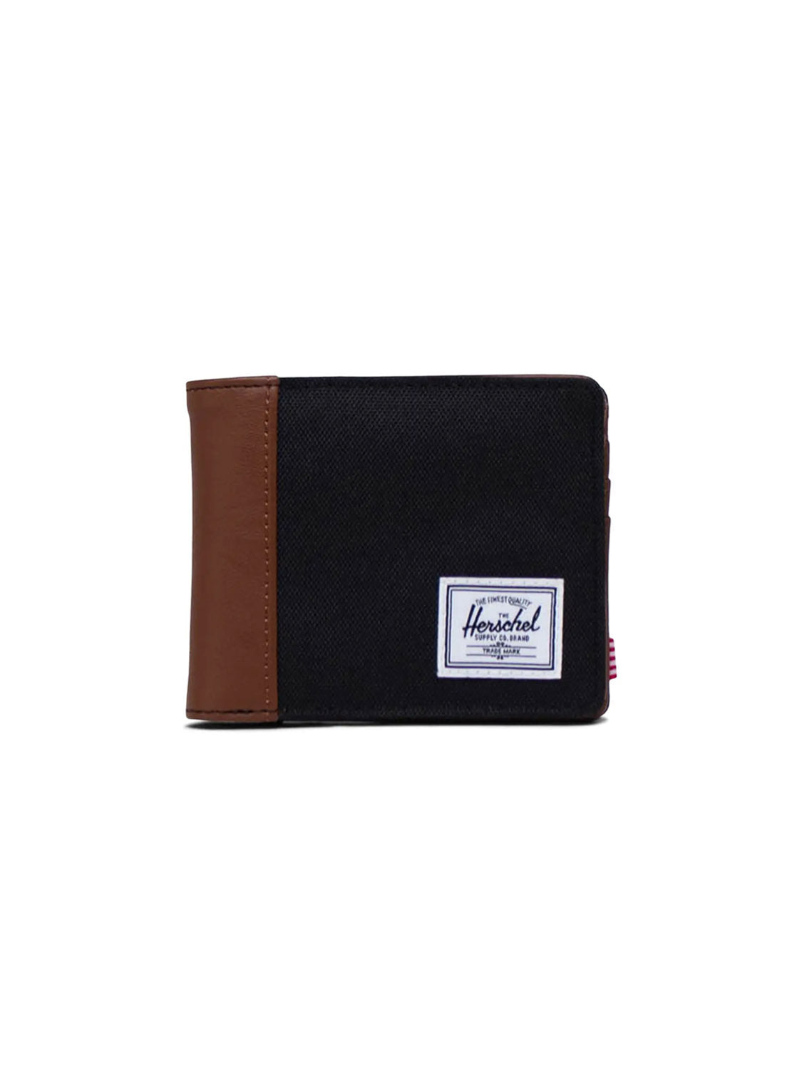 The Herschel Hank Wallet is a black fabric bi-fold with a brown leather accent on the left edge and a white rectangular brand label on the front. It features multiple card slots and is shown against a plain white background.