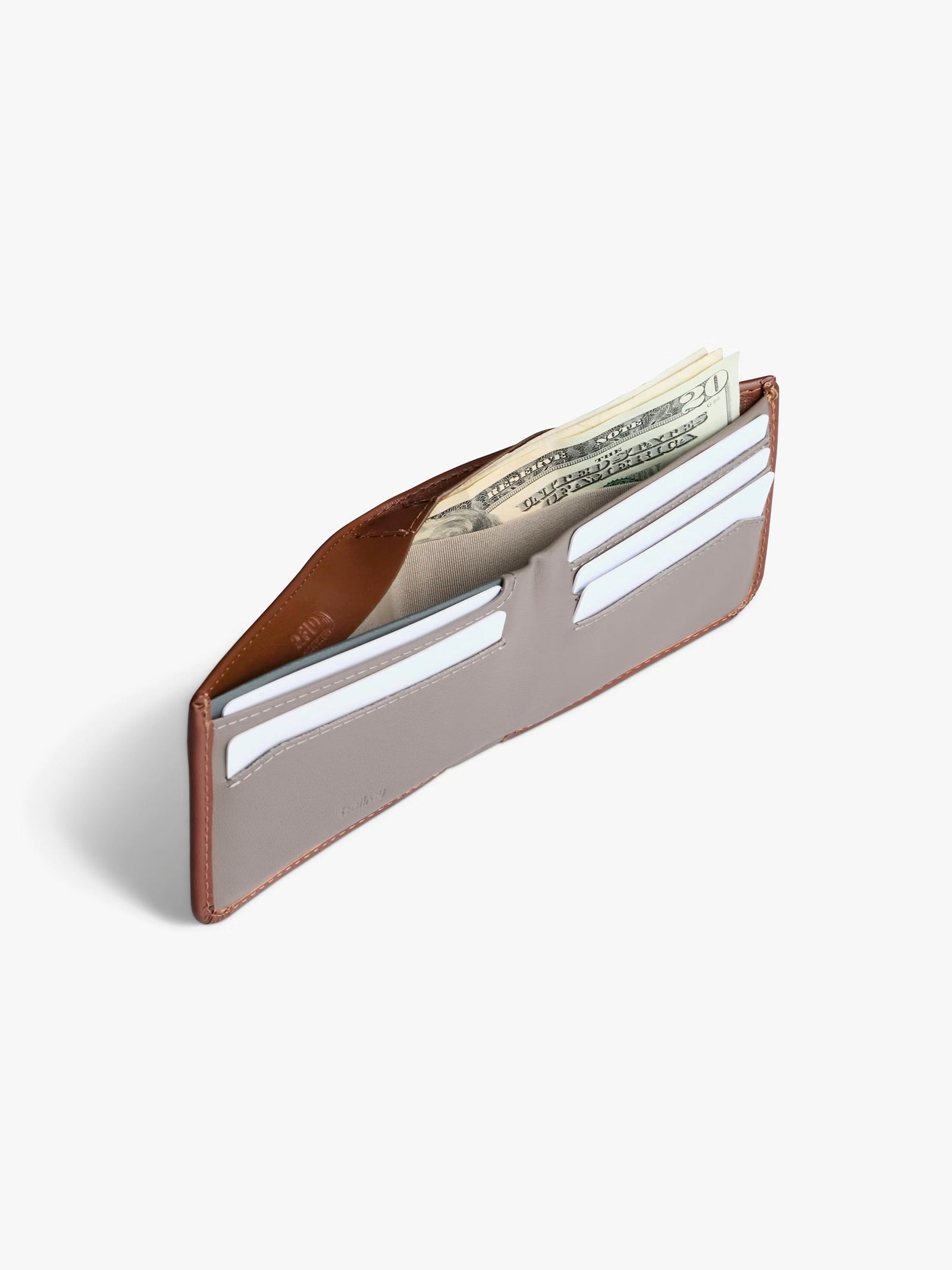 The Bellroy Hide and Seek Low Wallet, crafted from brown eco-tanned leather, is shown open on a white background with several credit cards and folded U.S. dollar bills inside.