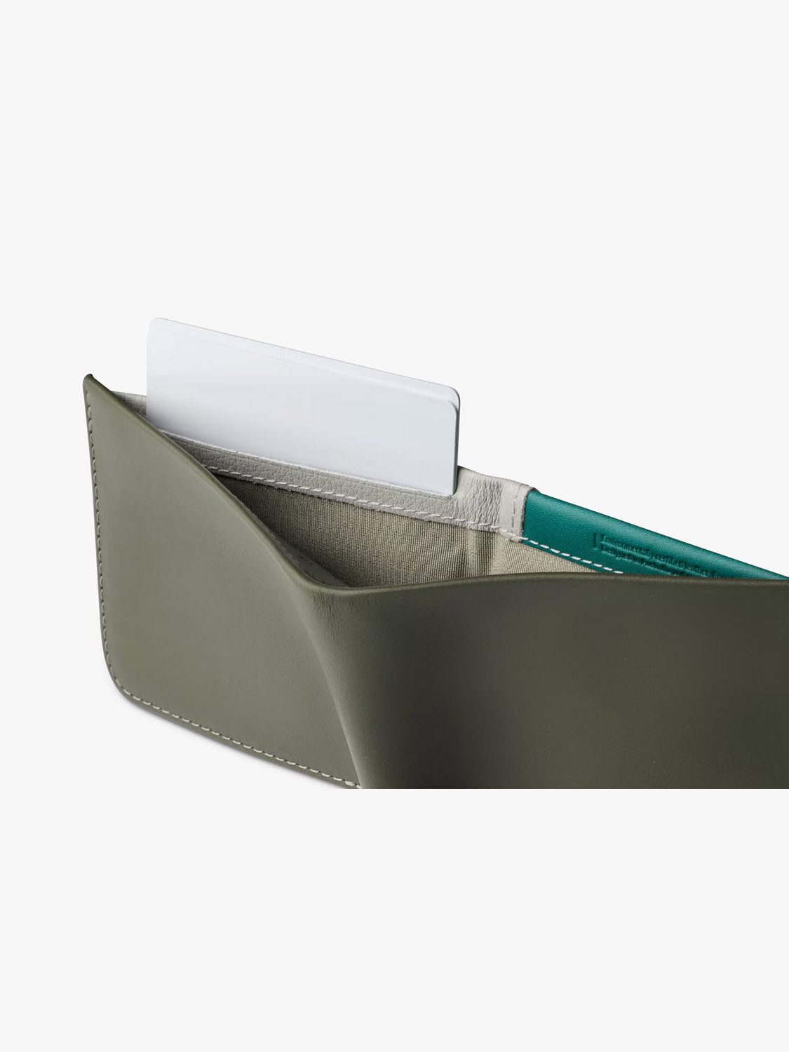A close-up of the Bellroy Hide and Seek Low Wallet in olive green eco-tanned leather with white stitching, partially open to show a white card inside its fabric-lined compartment.