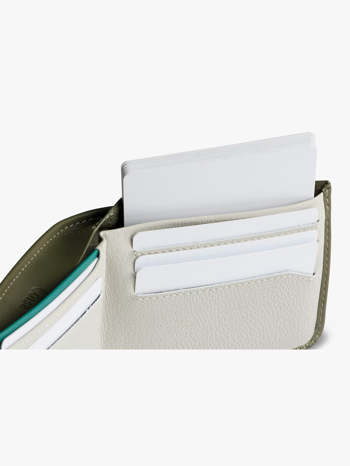A close-up of the Bellroy Hide and Seek Low Wallet, made from eco-tanned leather, displays several white cards slotted in its compartments against a plain, light background.