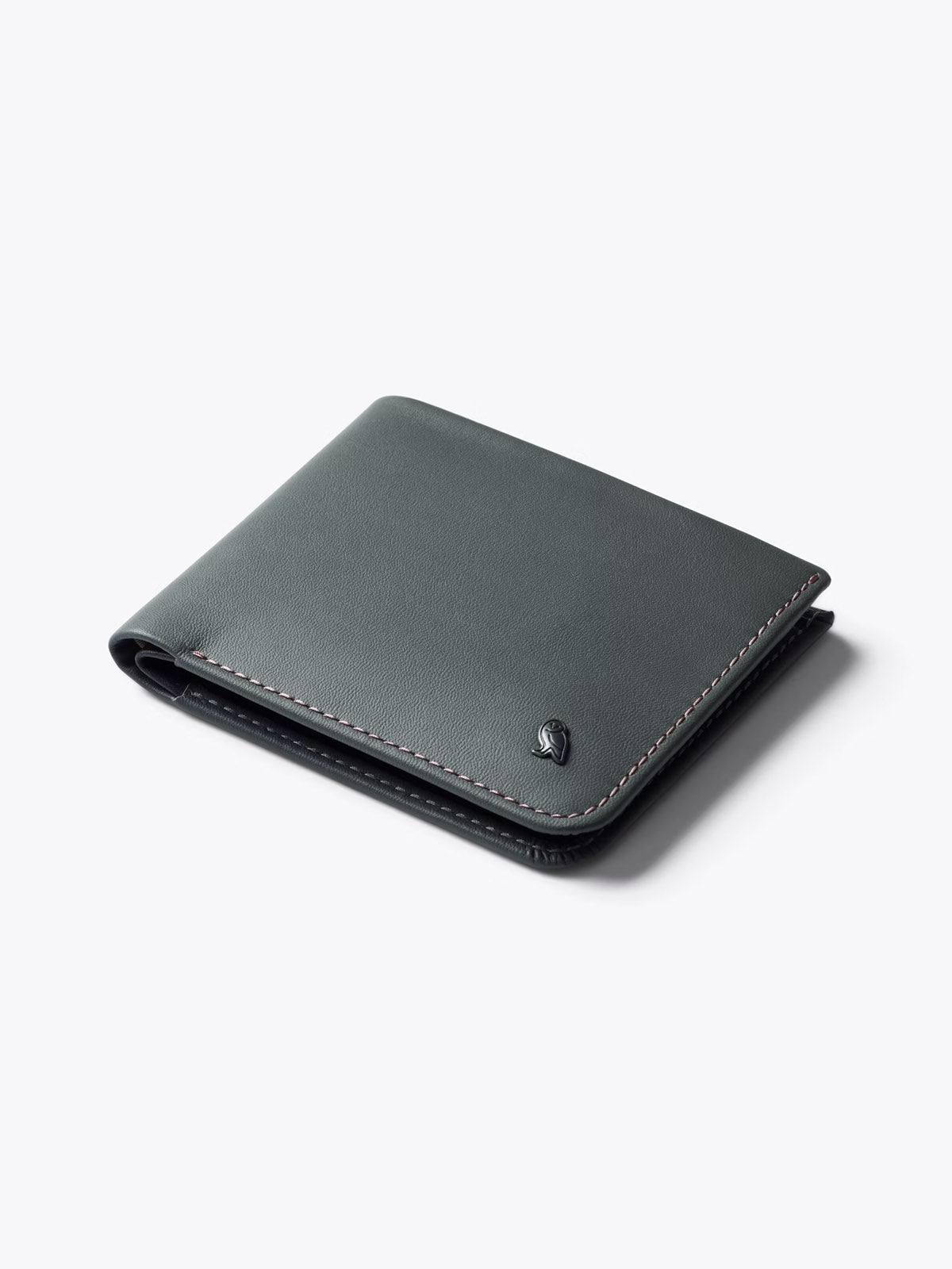 The Bellroy Hide and Seek Low Wallet is a slim, closed wallet made from black eco-tanned leather with visible stitching and a small embossed logo in the corner, displayed on a plain light gray surface.