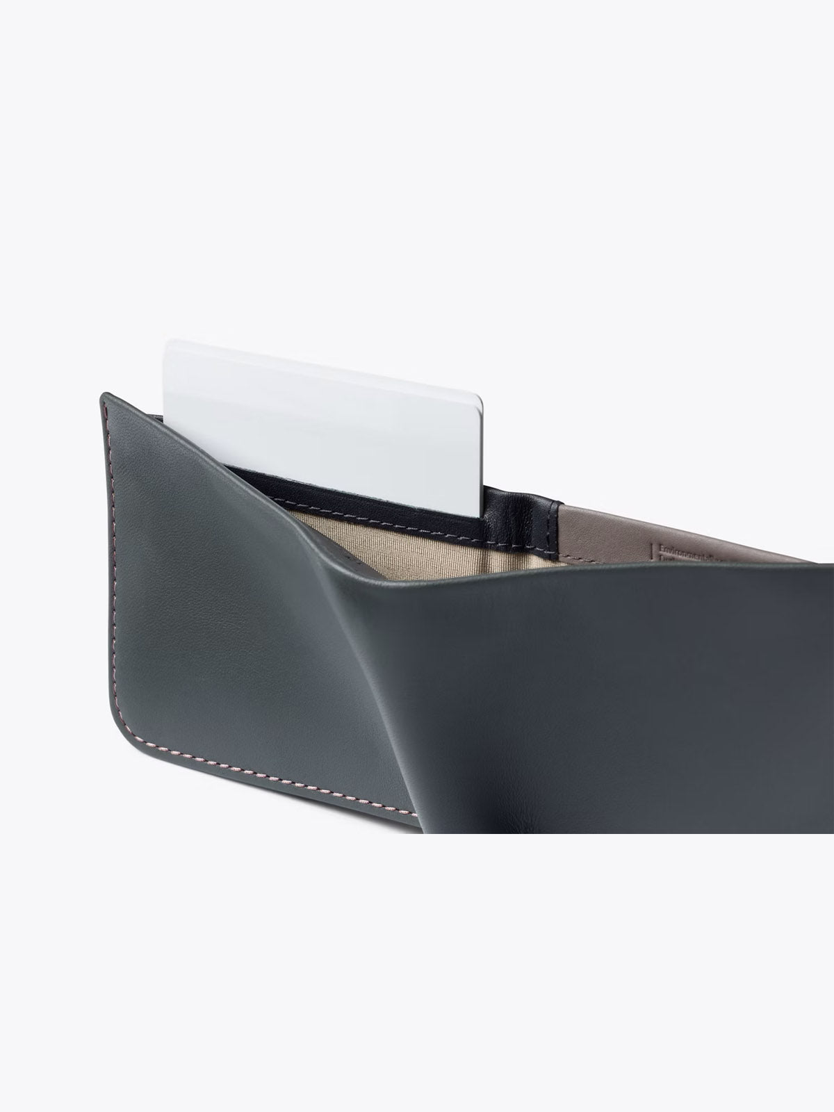 A close-up of the Bellroy Hide and Seek Low Wallet, open to reveal its beige interior and a white card partially tucked in a slot, set against a plain light background.