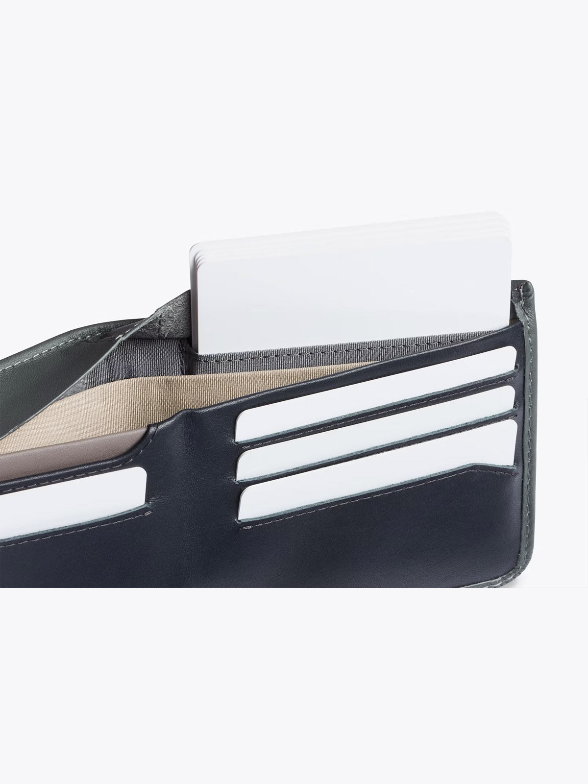 A close-up of the Bellroy Hide and Seek Low Wallet, crafted from black leather, displays several white cards and a beige card neatly arranged in its slim card slots against a plain white background.