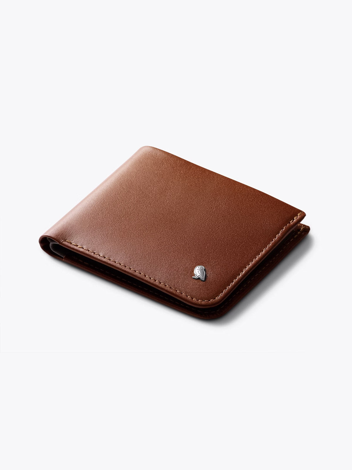The Bellroy Hide and Seek Low Wallet is a brown eco-tanned leather bifold, featuring a small metallic emblem on the corner, displayed closed on a plain white background.