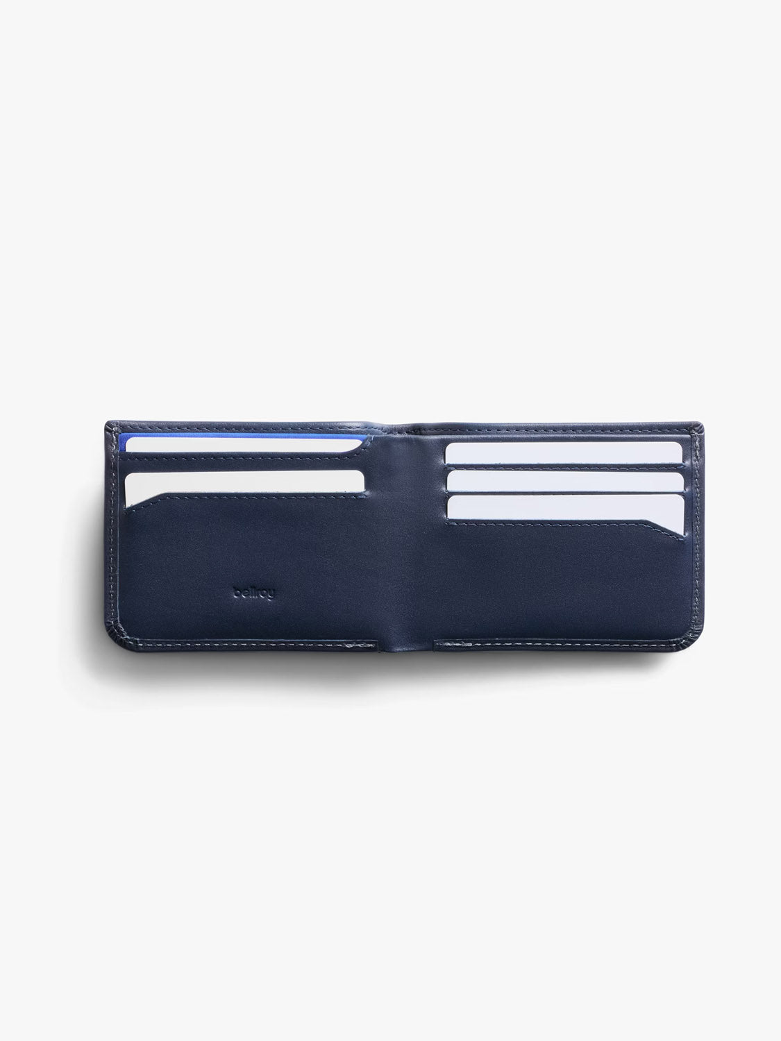 The Bellroy Hide and Seek Low Wallet in navy blue eco-tanned leather is open, showing multiple card slots with white cards on both sides, set against a white background.