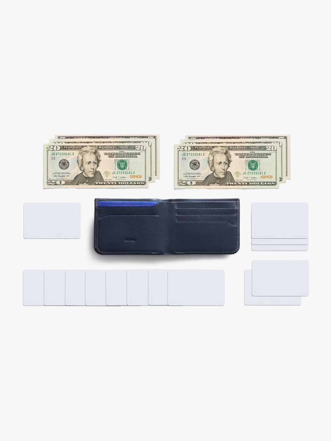 A Bellroy Hide and Seek Low Wallet in navy blue eco-tanned leather lies open and empty on a white background, with white cards and neat stacks of U.S. $20 and $5 bills arranged above it.