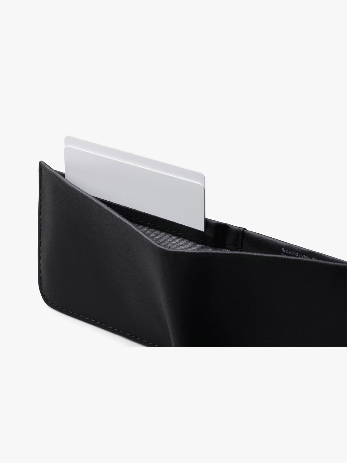 A close-up of the Bellroy Hide & Seek Innovera™ Edition wallet, crafted from premium leather alternative, with a white card partially visible in one compartment, set against a plain white background.