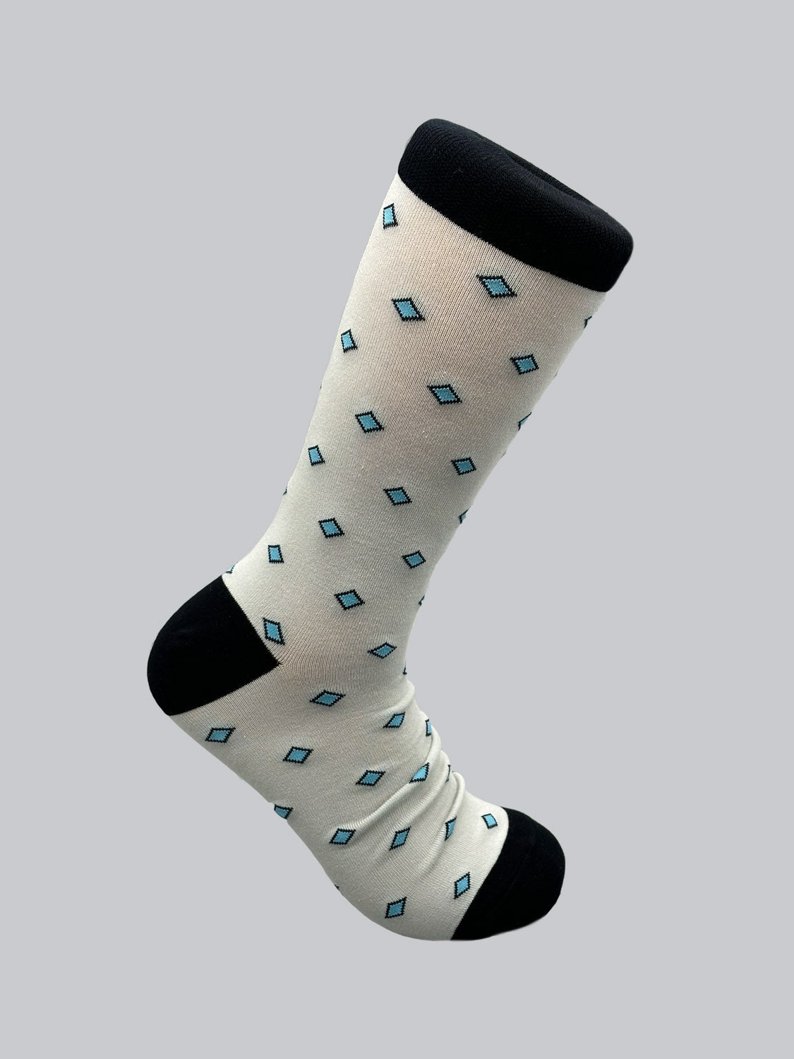 The Hishi Graphic Sock by ID Menswear is a white sock with black toes and cuffs, crafted from combed cotton. It features a Japanese Hishi pattern with small blue diamonds against a gray background.