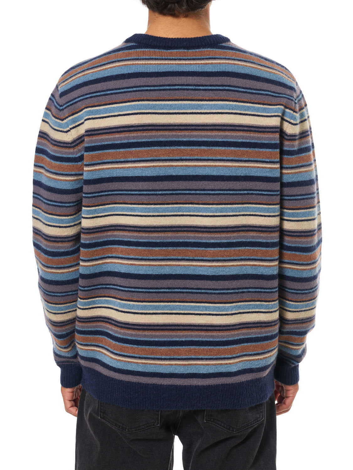 A person is photographed from the back wearing Katin's Hitch Sweater, a long-sleeved piece featuring a custom stripe pattern in blue, brown, cream, and tan, made from ultra-soft blended yarn, paired with dark pants.