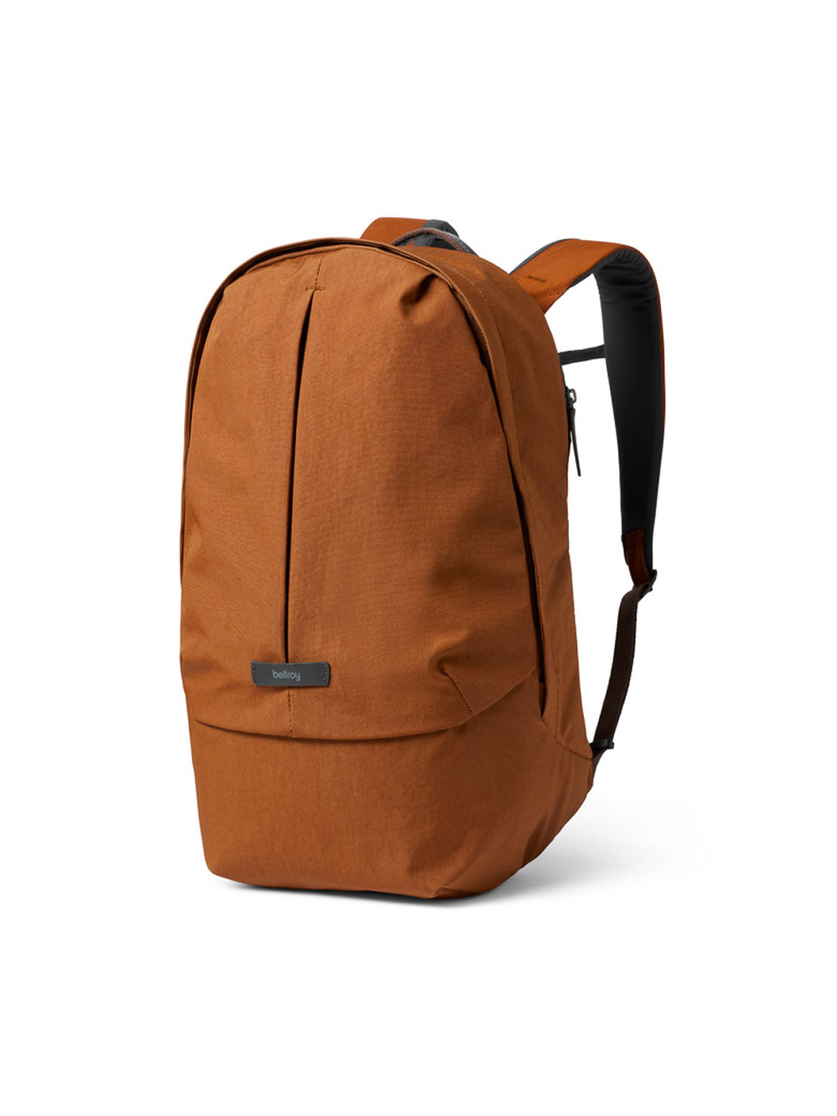The Bellroy Classic Backpack Plus - 24L is rust-colored with a minimalist dual-compartment design, front vertical seam, black padded straps, water-resistant recycled fabric, and a small logo tag on the front.