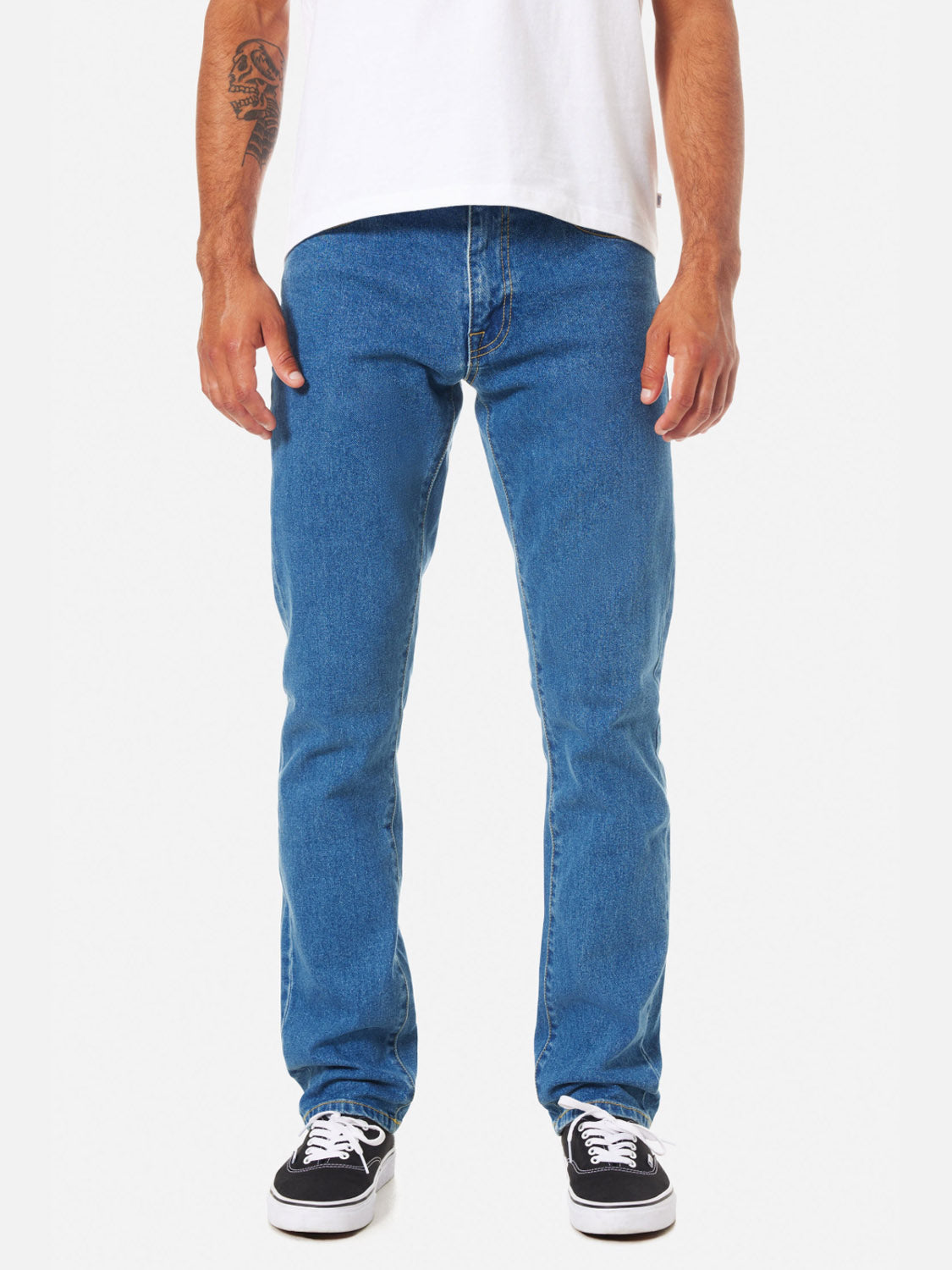 A person wearing Katin Jacob 71 Slim Straight Pants in blue with classic 5-pocket styling is paired with black-and-white sneakers, standing against a white background. Only the lower torso and legs are visible.