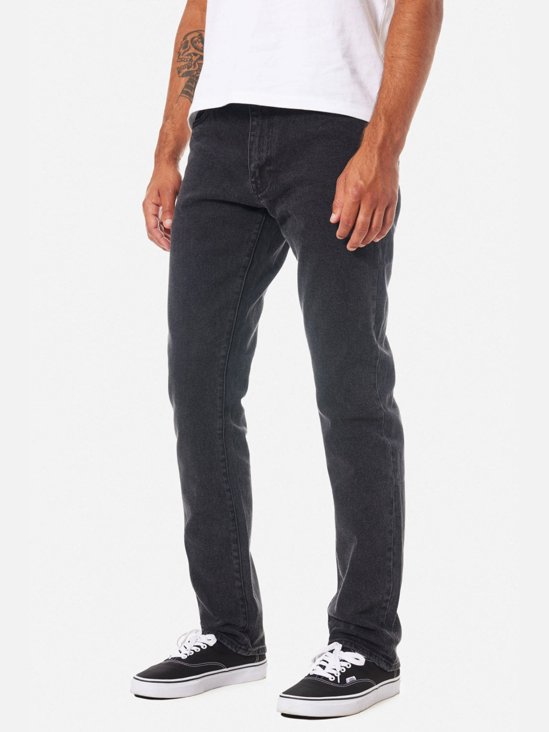 A person is shown from the waist down wearing Katin’s Jacob 71 Slim Straight Pants in black, styled with a white T-shirt and black-and-white sneakers, standing against a plain white background.