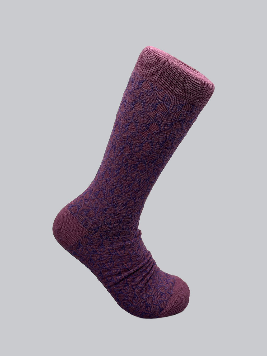 The Fall Graphic Socks by ID Menswear are crafted from soft, breathable combed cotton and feature a dark geometric pattern on a single purple sock with solid top band, heel, and toe. Theyre showcased on a light gray background for an elegant contrast.