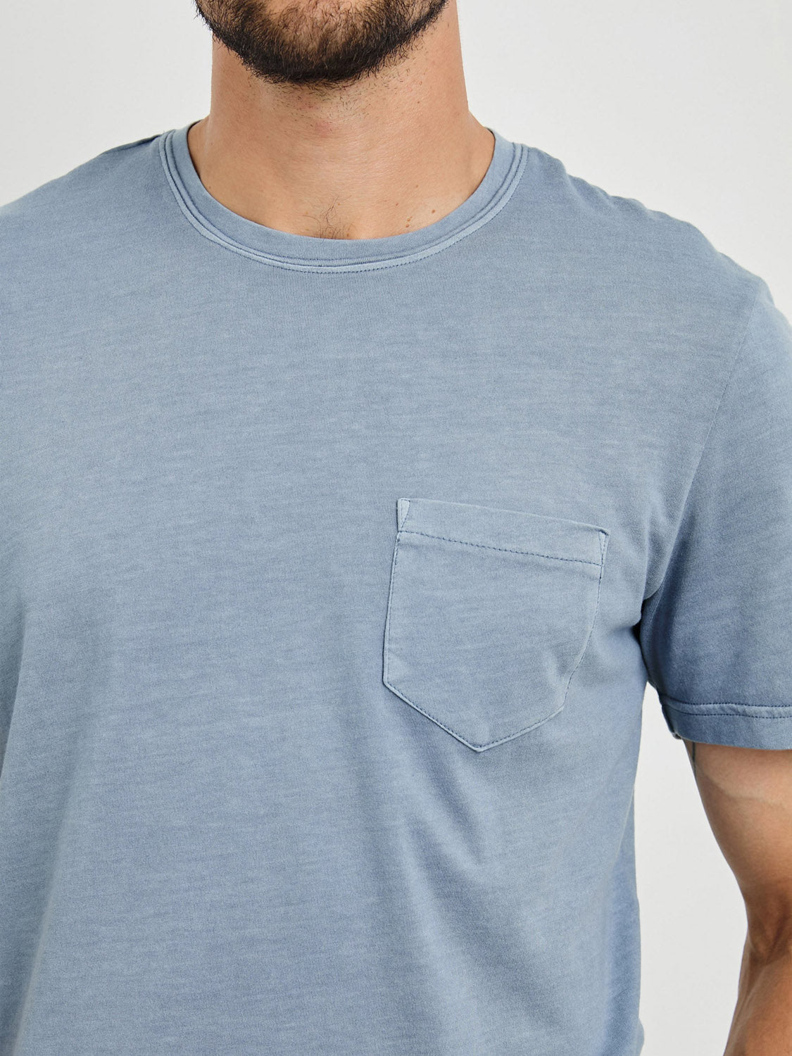 Against a neutral background, a person models the Rails Johnny Tee in light blue. Crafted from super-soft cotton modal with a pocket on the left side, the shirt showcases its classic fit as the focus is on the upper torso and chest area.