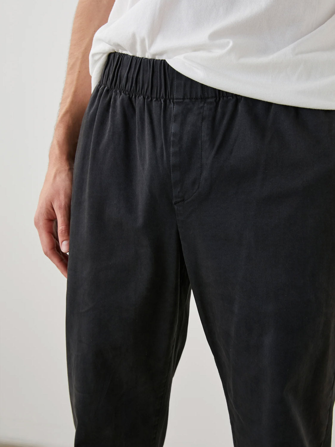 Someone is wearing Rails Julian Pants with an elastic waist and a white T-shirt. Only the torso and upper legs are visible, highlighting the relaxed fit and casual style. The background is plain and softly lit.