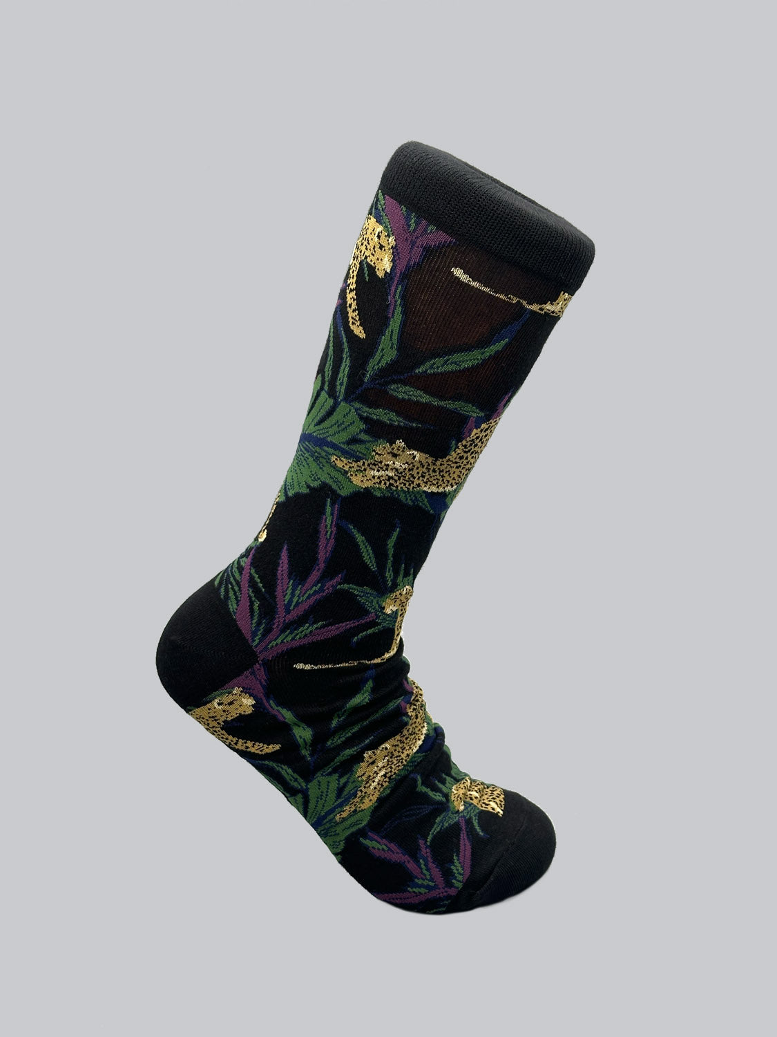 Introducing ID Menswears Jungle Graphic Socks crafted from combed cotton. These vibrant socks feature yellow leopards and green jungle foliage, with purple accents on a dark background, ensuring both comfort and style.