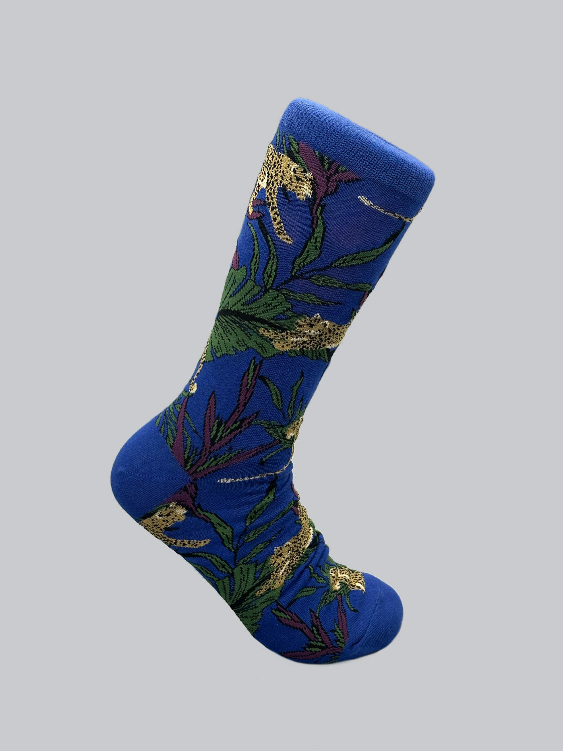 The Jungle Graphic Socks by ID Menswear are crafted from combed cotton, offering comfort with their colorful, intricate pattern of tropical leaves and leopards.