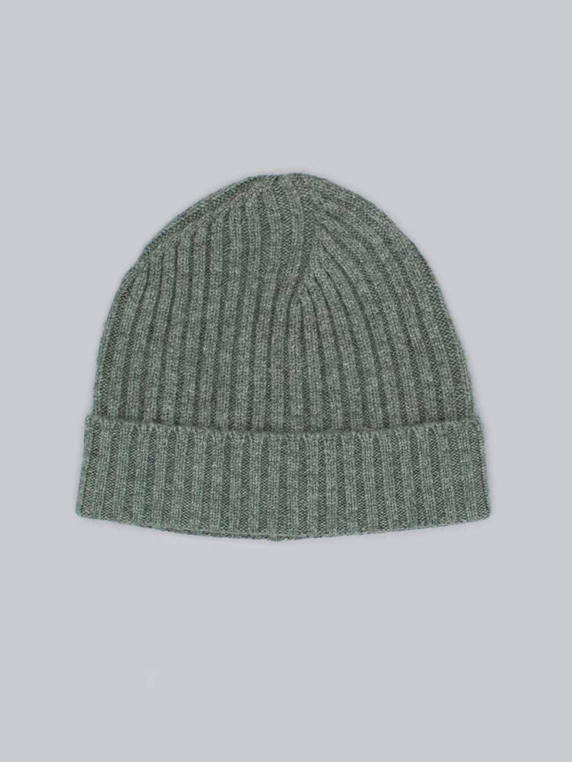 The Kailash Merino Wool Beanie by ID Menswear is a green knitted hat featuring a ribbed pattern and folded brim, providing warmth and softness for outdoor adventures. Its displayed against a light gray background.