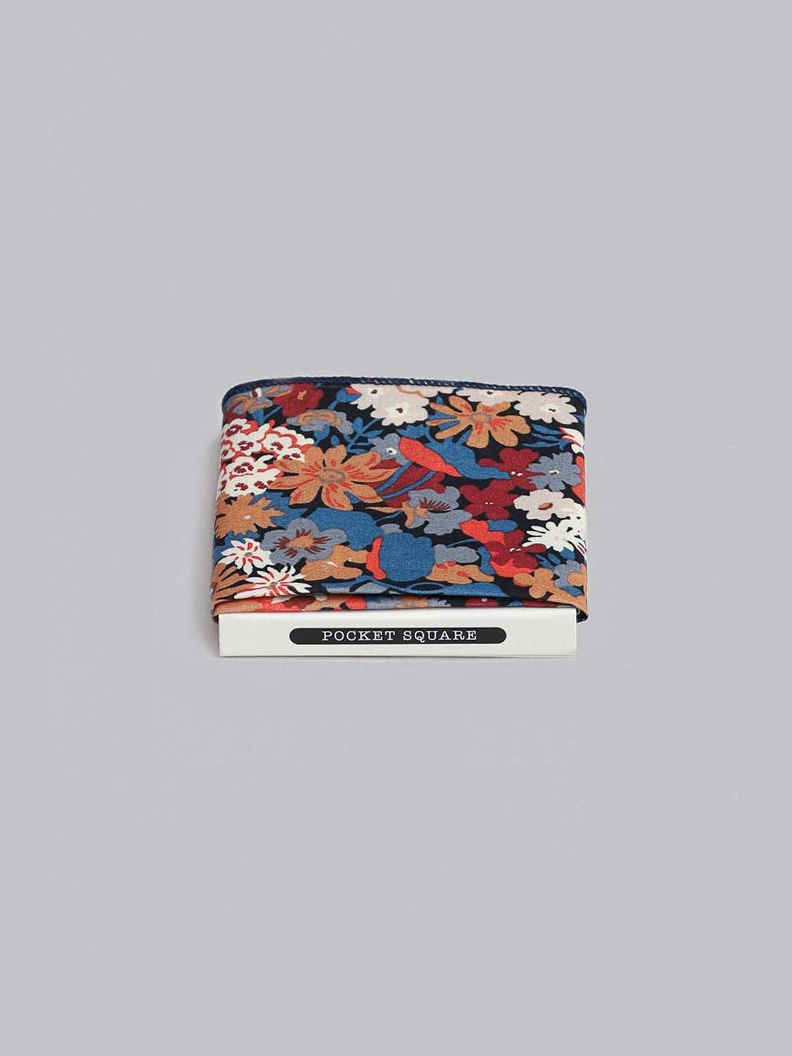 The Liberty™ Kanazawa Pocket Square by ID Menswear, made from luxurious Liberty of London Tana Lawn cotton and featuring a vibrant floral pattern, is folded on a white POCKET SQUARE card against a light gray background.