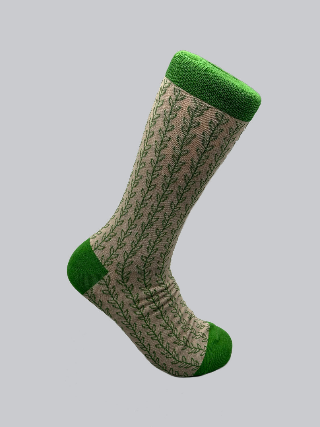 Discover ID Menswears Kombu Graphic Socks: a single beige sock featuring green leaf patterns with solid green toe, heel, and cuff. Made from combed cotton for a soft feel and set against gray, these breathable socks merge comfort with style.