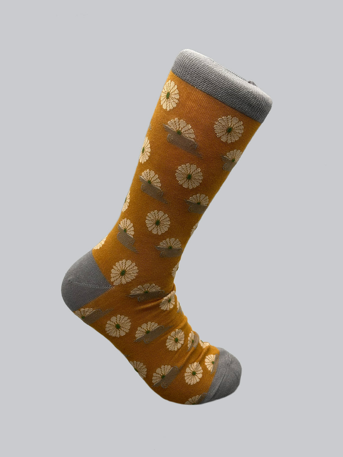 The Kiku Graphic Socks by ID Menswear showcase a yellow backdrop adorned with white flowers. Made from premium combed cotton, the sock features gray toe, heel, and cuff. Against a plain gray background, the floral design stands out vibrantly.