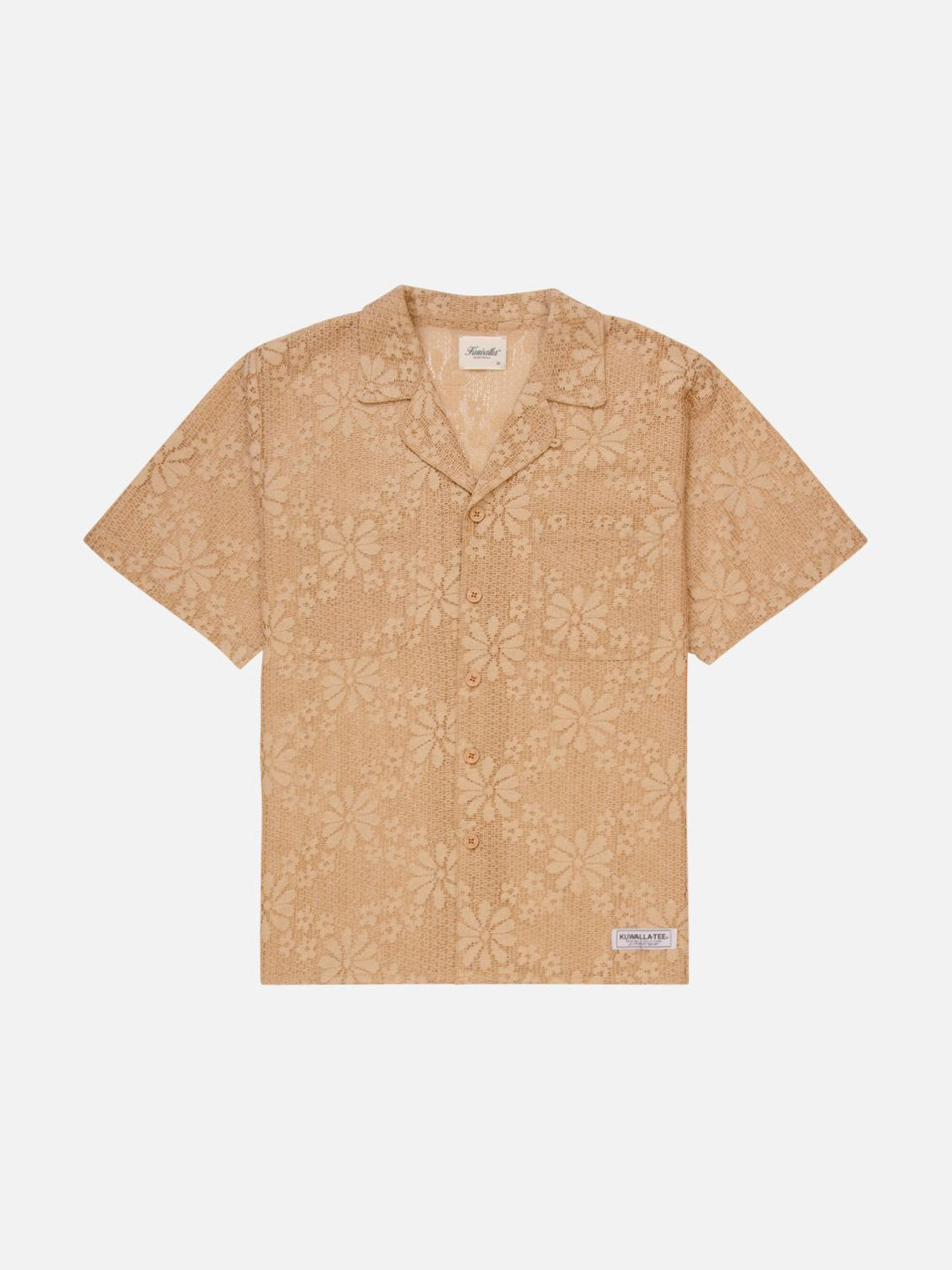 The Kuwalla Lace Yacht Shirt is a tan short-sleeve shirt with a subtle floral print, made from lightweight fabric. It features a button-up front, notched collar, and includes a small brand tag on the lower left side. Displayed on a white background, it showcases its classic fit.
