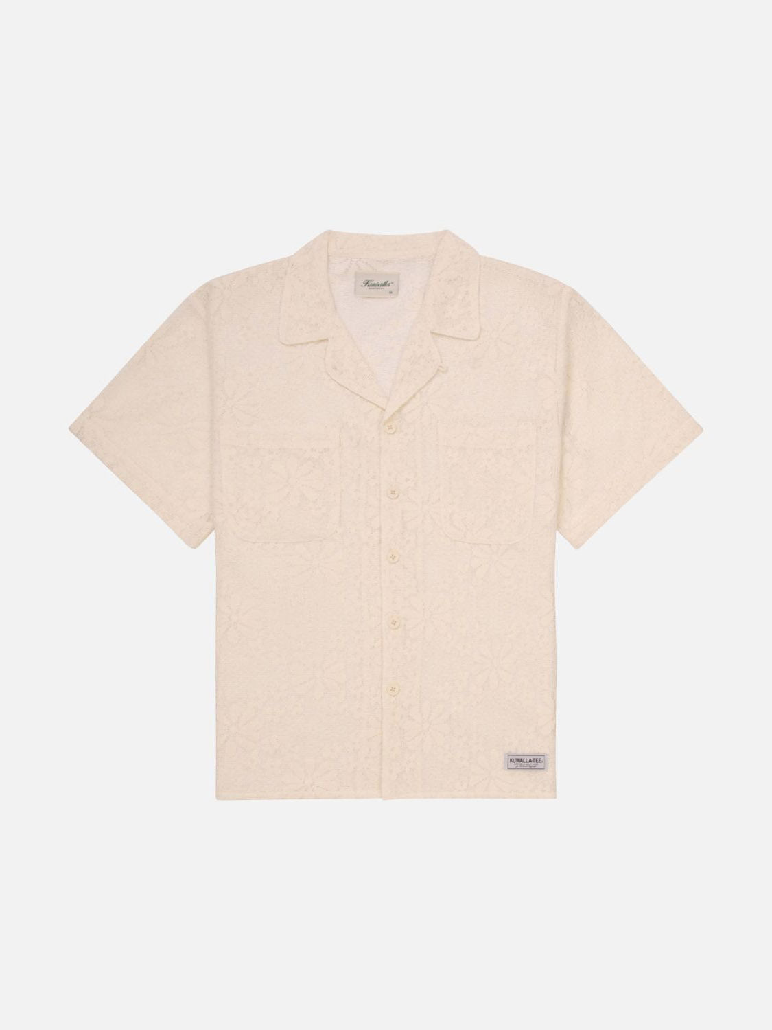 The Kuwalla Lace Yacht Shirt, a beige short-sleeve button-up crafted from lightweight fabric, features a subtle floral pattern, classic fit, single chest pocket, and small label near the hem. Displayed laid flat on a white background.