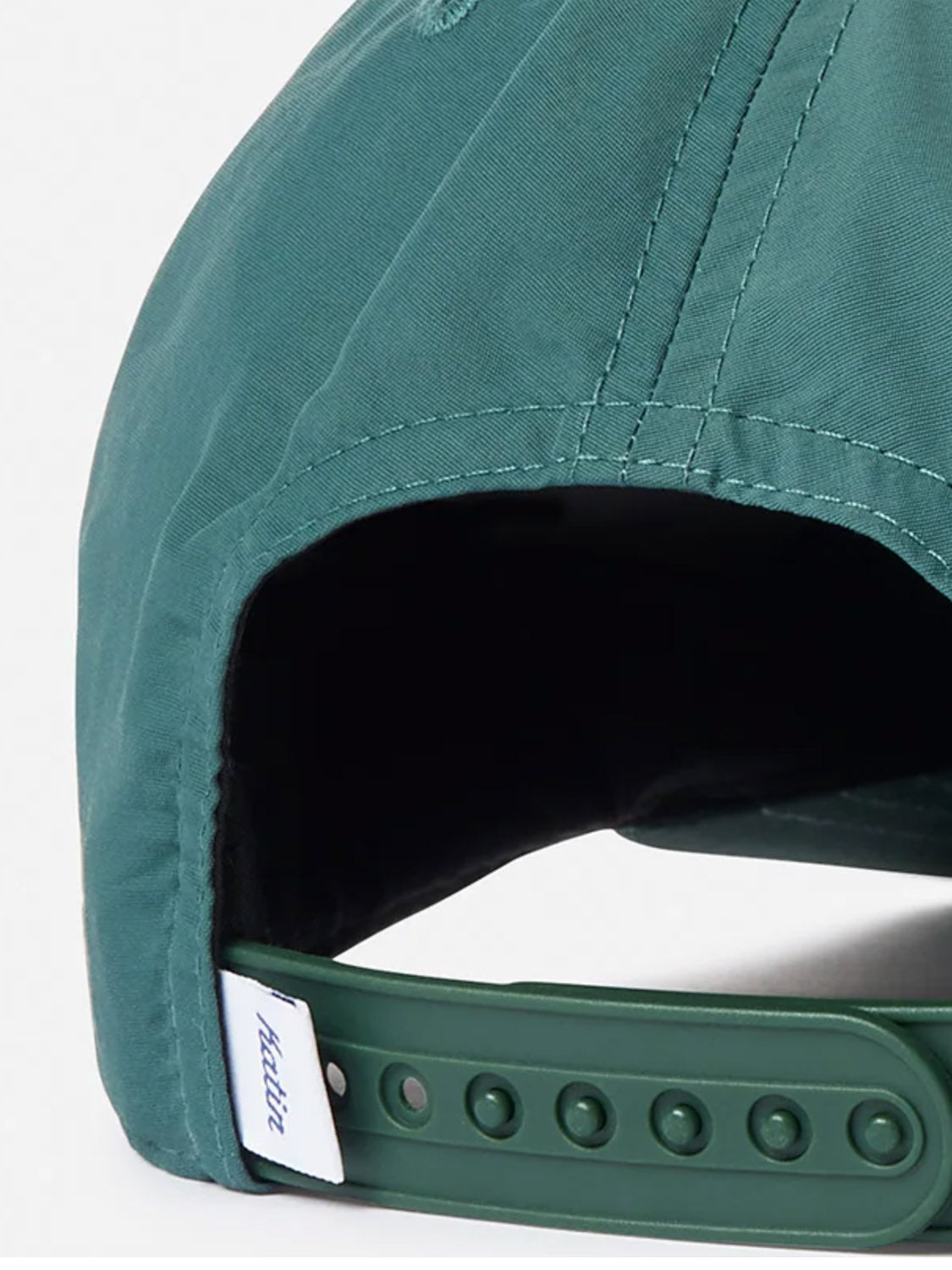 A close-up of the back of the Katin Largo Hat, a green 5 panel cap made from recycled nylon, features an adjustable snapback closure and a small white tag with blue text tucked into the opening.