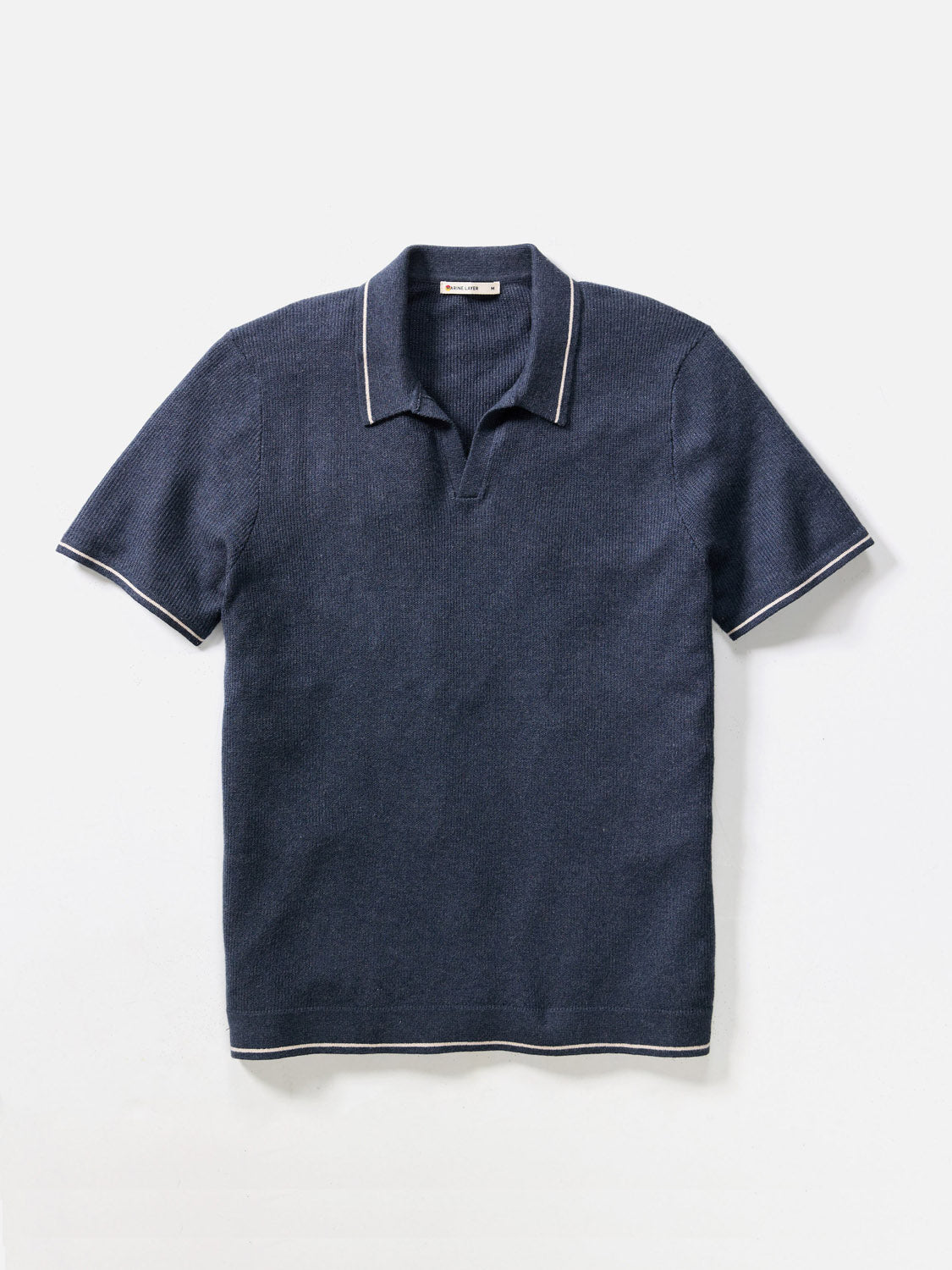 The Marine Layer Liam Sweater Short Sleeve Polo, featuring dark blue knit fabric with white trim on the collar, sleeves, and hem, is shown laid flat on a white background.