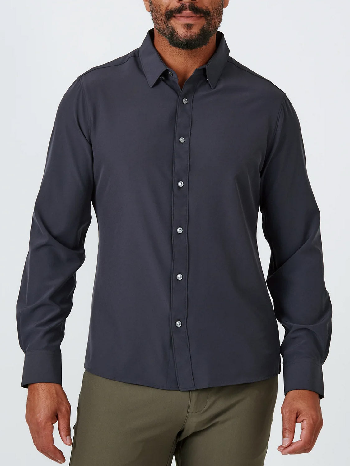A man stands against a plain light background wearing the ID Menswear Liberty 4-Way Stretch Shirt in dark gray and olive green pants.