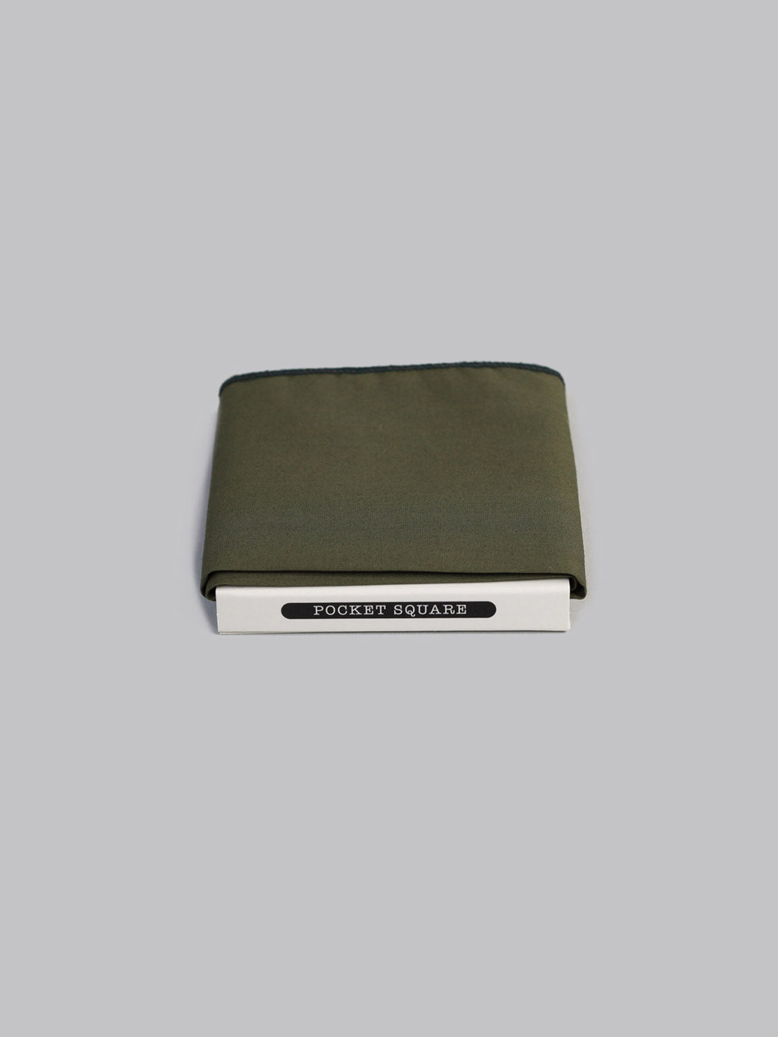 A folded Liberty™ Moss Pocket Square by ID Menswear, handmade from Tana Lawn cotton, rests in a white POCKET SQUARE® box against a plain light gray background.