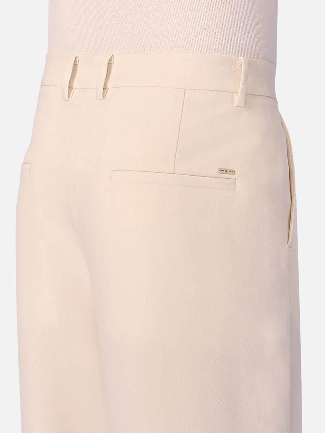 Close-up of the back and side of a person wearing Industrie’s The Lightweight Lusso Pant, featuring pleated high-waist tailoring and slit back pockets in cream, shown against a plain light background.