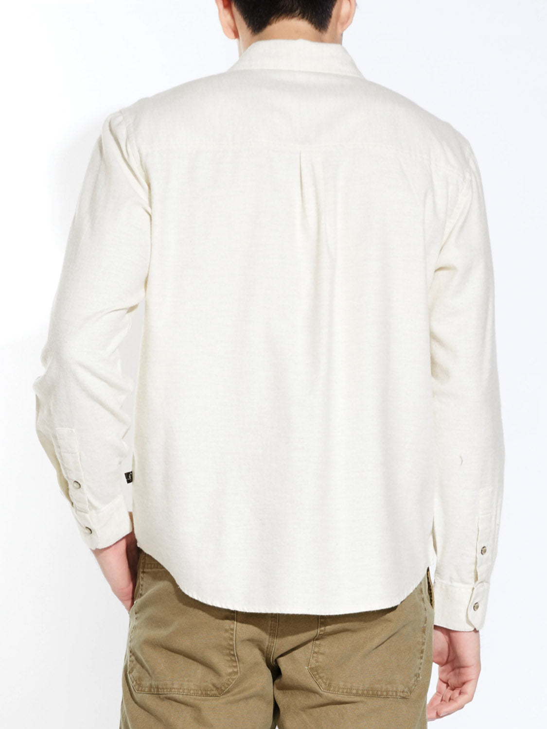 A person stands facing away in the Civil Society Linwood Relaxed Fit Western Shirt—an off-white, long-sleeved men's cotton shirt with faux pearl snaps, worn untucked with light brown pants against a plain white background.