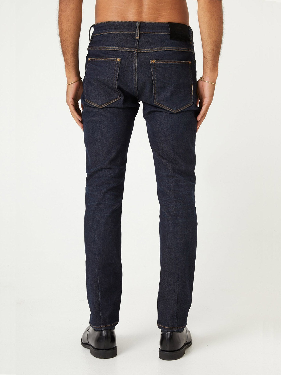A man, barefoot and shown from the back, wears ID Menswear's Lou Slim - Typecast jeans with visible stitching, standing against a plain white background.
