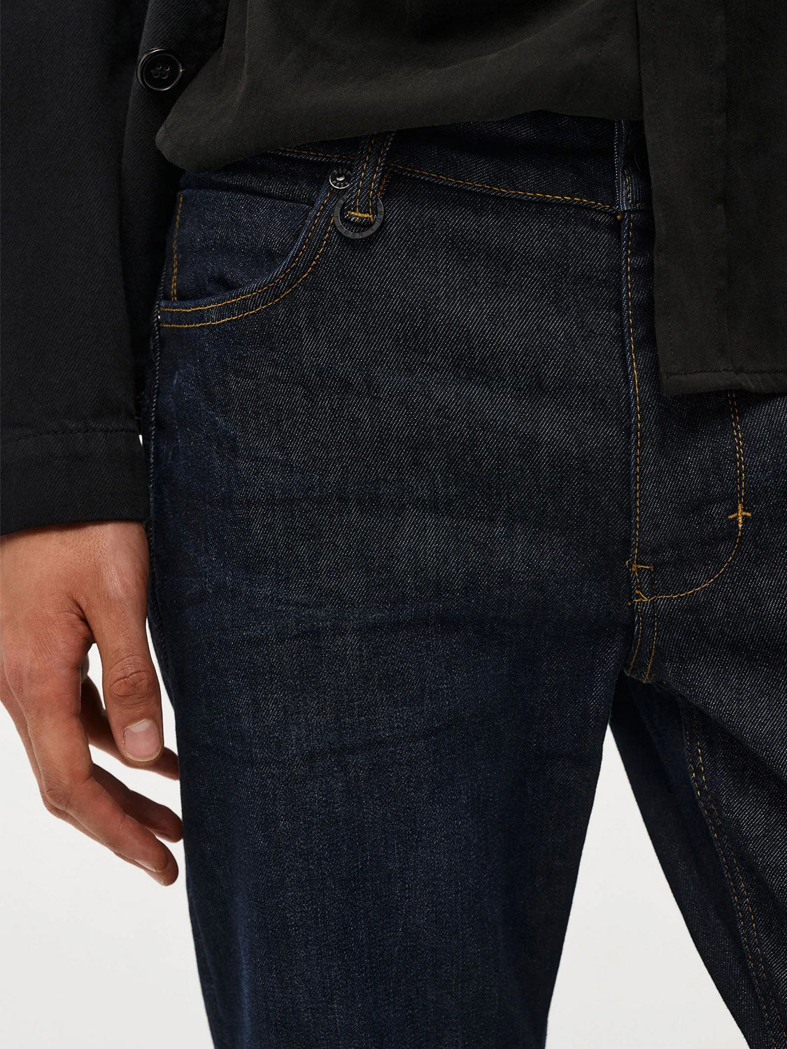 A person wearing ID Menswear's Lou Slim - Typecast jeans and a black shirt stands with their left hand relaxed by their side, partially visible against a light background.
