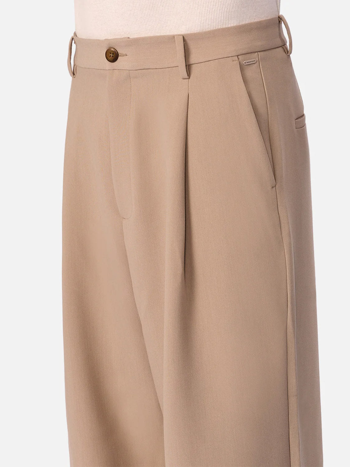 Close-up of Industrie’s Lightweight Classic Lusso Pant - Stone, featuring a pleated front, side pockets, and belt loops. Styled with a tucked-in light top, these wide leg pants provide elegant comfort.