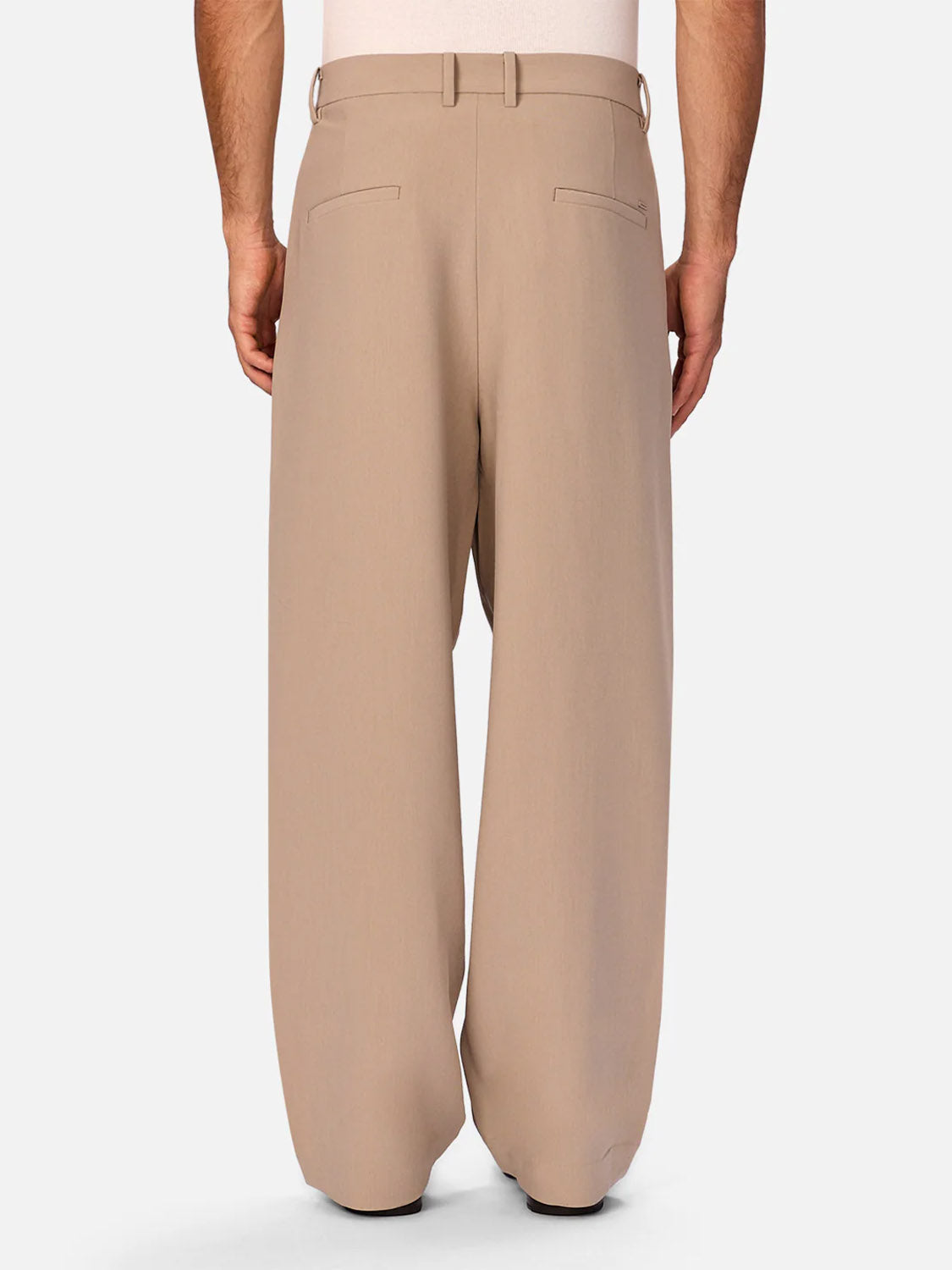 A person is shown from the back wearing Industrie’s Lightweight Classic Lusso Pant in Stone, featuring a high waist, wide leg, belt loops, and two back welt pockets with a tucked-in white top for a relaxed look.
