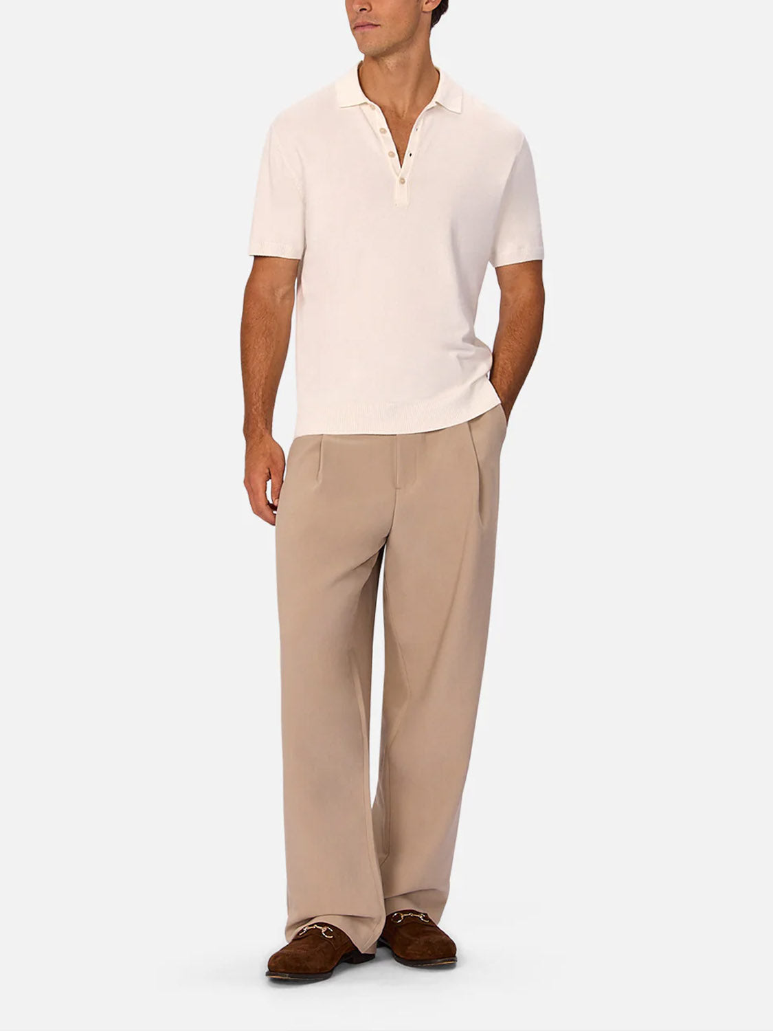 A person stands wearing a cream short-sleeve polo with buttoned collar, Industrie’s Lightweight Classic Lusso Pant in Stone, and brown suede loafers, posing against a plain light background.