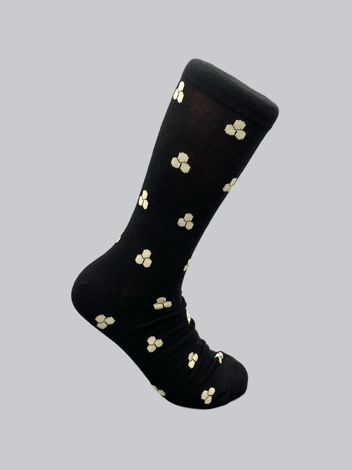 The Mae Graphic Socks by ID Menswear are black with small, light-colored four-petal flowers on a plain gray background. Made of premium combed cotton for comfort, these socks elegantly capture the essence of Japanese patterns.
