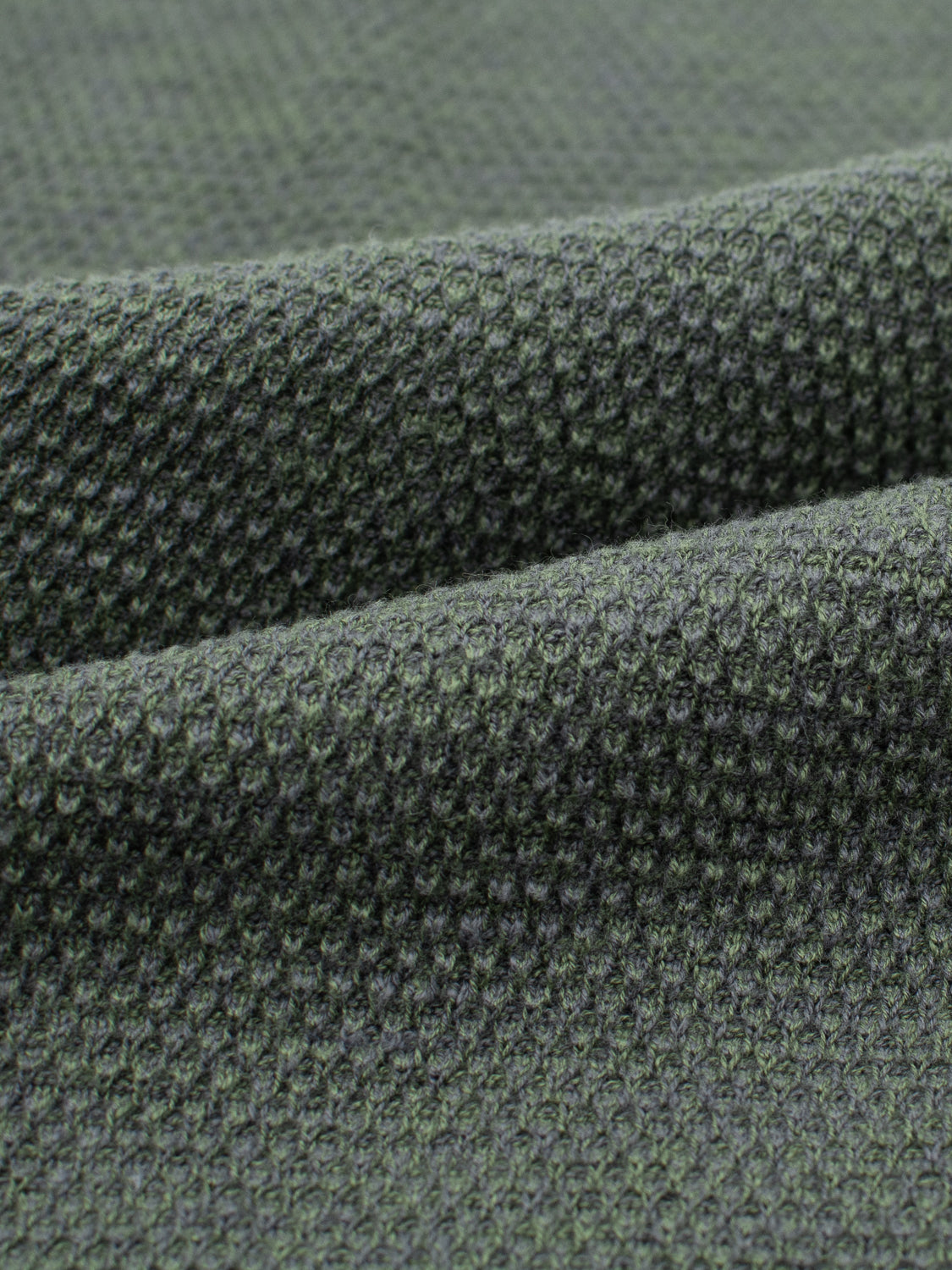 Close-up of the Malta Rolled Neck Sweater Tee by ID Menswear, showcasing its green textured fabric with a raised waffle weave. The thick and soft cotton material forms gentle folds, suggesting a comfortable fit.