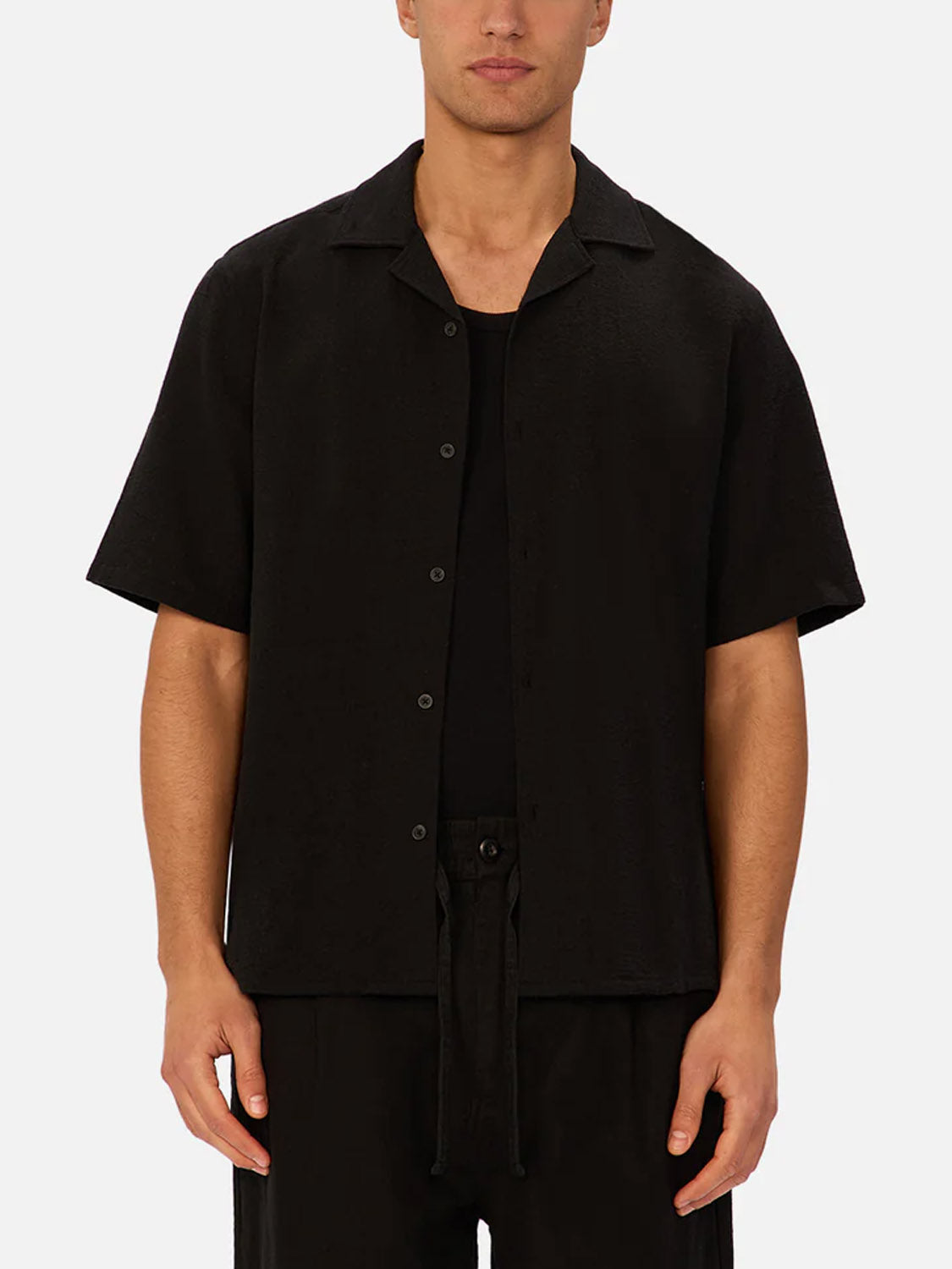 Someone wearing the Industrie Marbella Short Sleeve Shirt over a black top and black pants, standing against a plain light background.