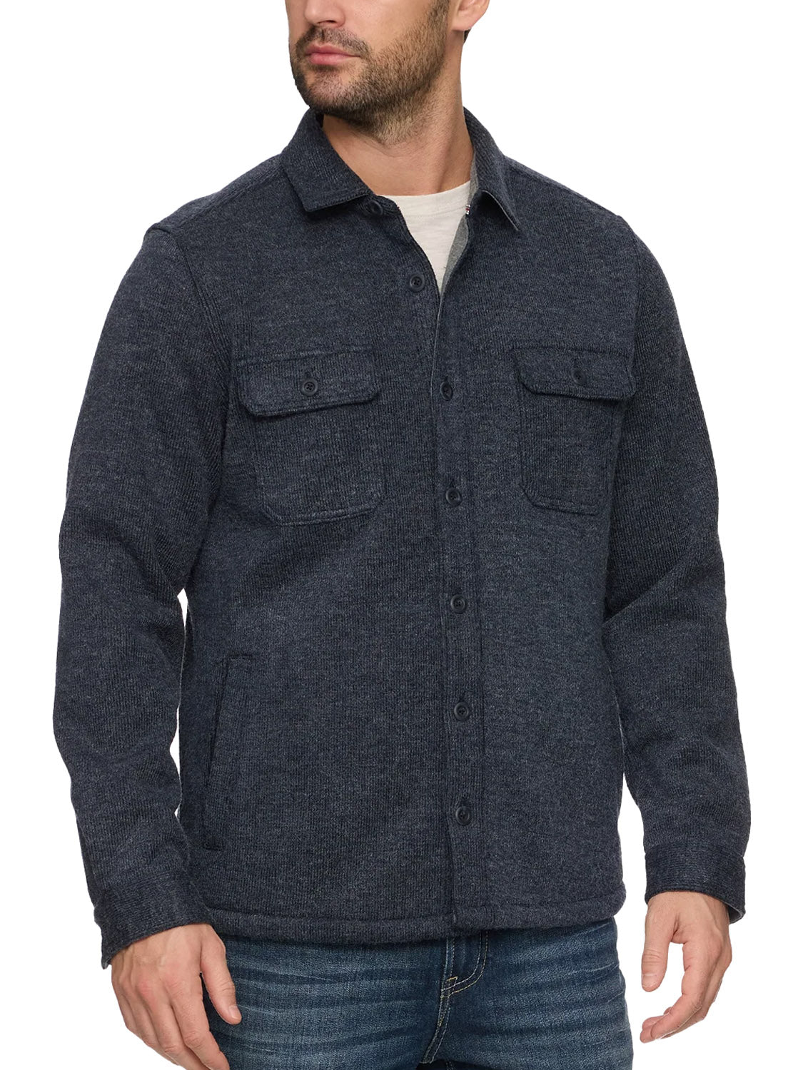 A man wears the Flag and Anthem Mason Fleece Lined Shirt Jacket in dark gray, featuring chest pockets and a cozy fleece interior, layered over a white shirt and blue jeans against a white background.