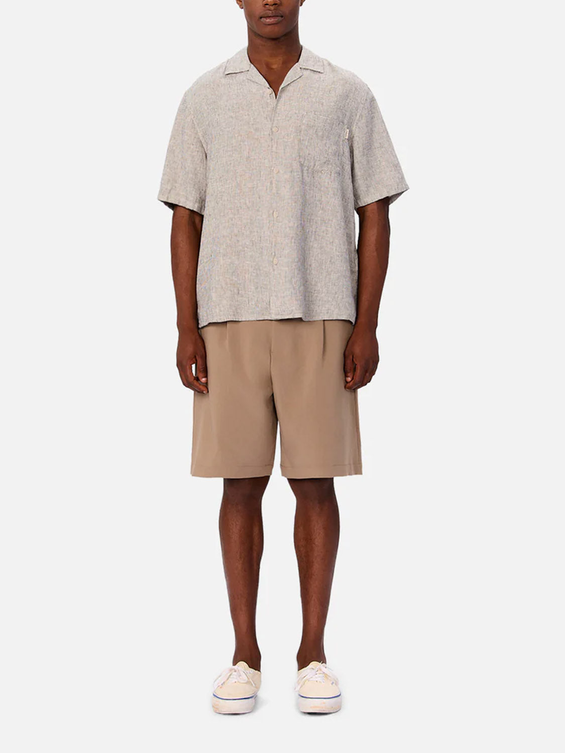 A person stands facing forward, wearing the Industrie Melrose Short Sleeve Shirt in light grey, tan knee-length shorts, and off-white sneakers against a plain white background.