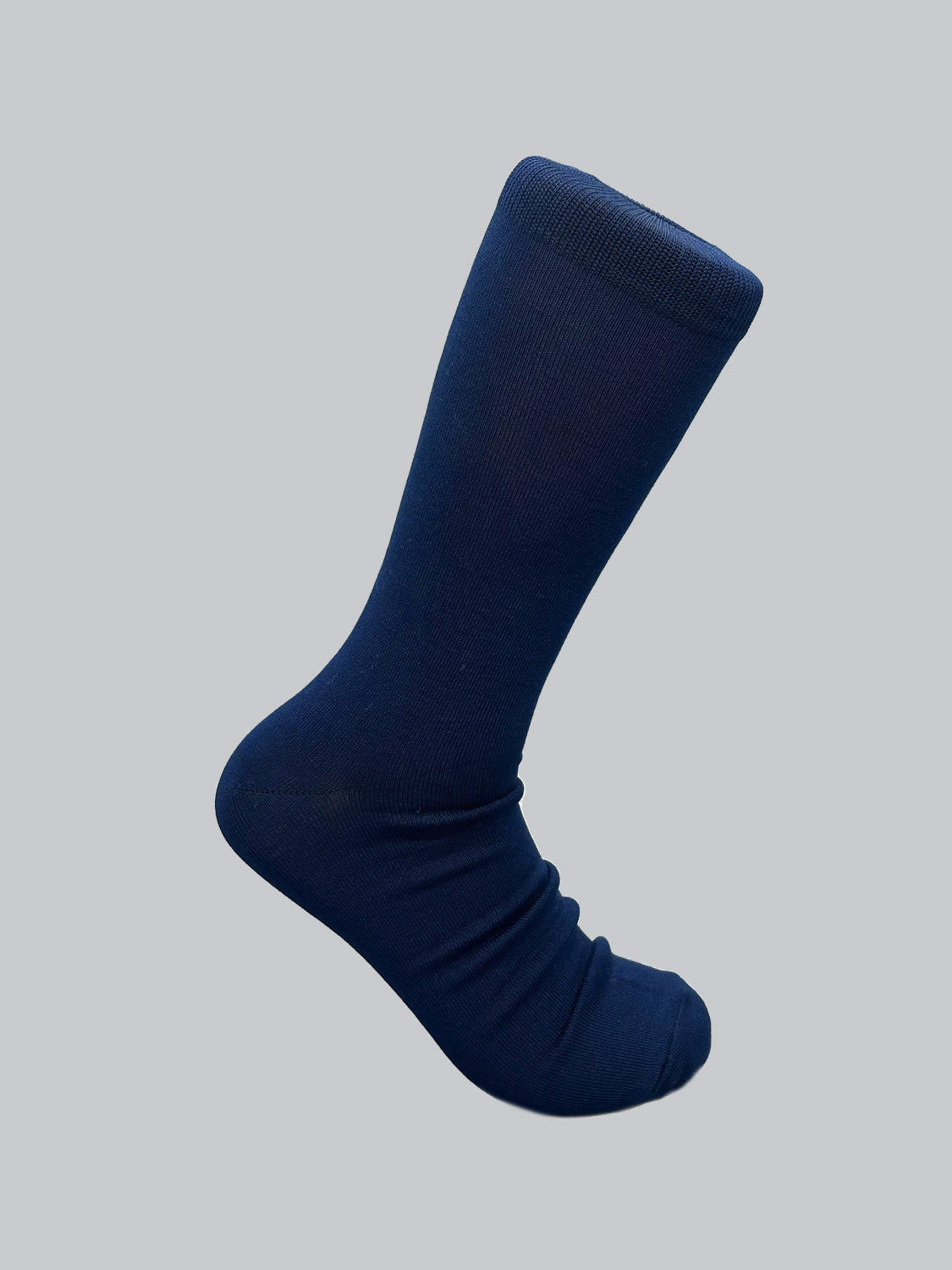 A medium-length, dark blue sock from ID Menswears Mercerized Cotton Socks line is displayed against a light gray backdrop. Crafted from mercerized cotton, it stands upright with the foot portion slightly wrinkled, suggesting softness, durability, and a subtle sheen.