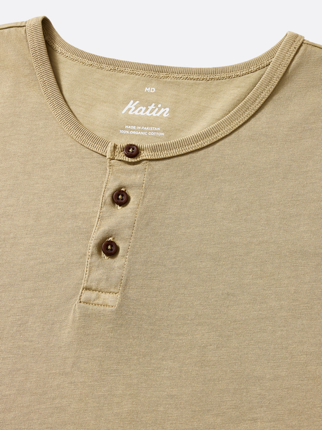 A close-up of the Katin Mesa Henley in beige, made from organic cotton. It features a ribbed collar, three-button placket with dark buttons, and a soft, lightweight feel—ideal for everyday wear.