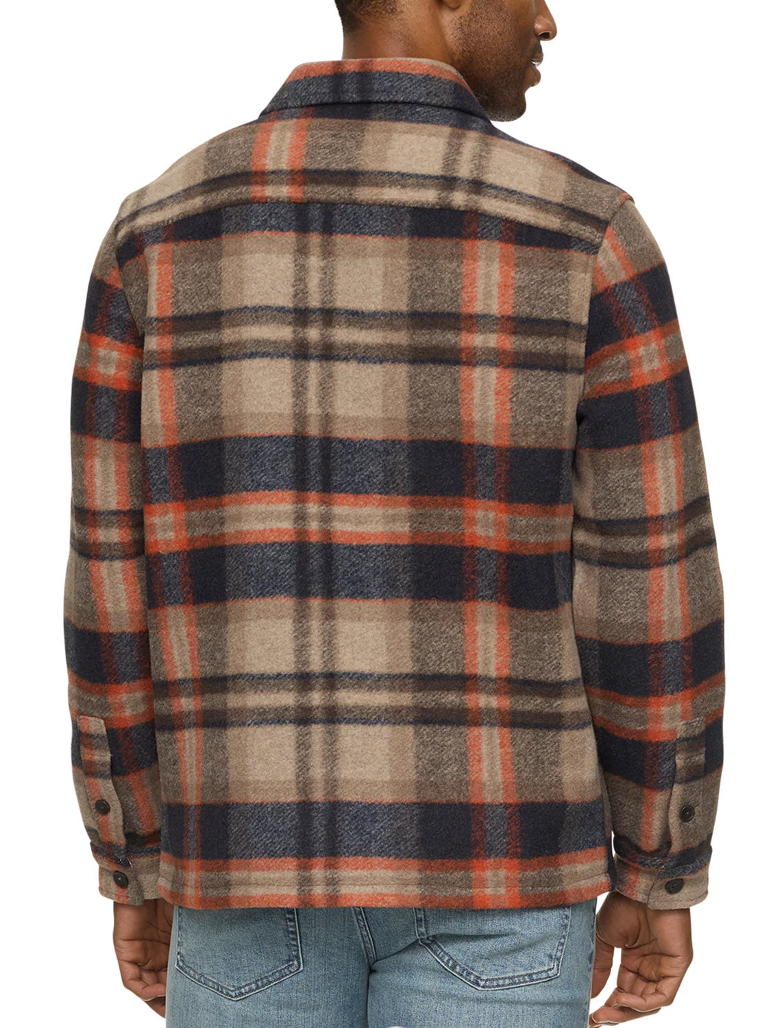 A man is seen from the back wearing the Flag and Anthem Midland Jacket, a tan, navy, and orange plaid shirt jacket made from soft brushed fabric, paired with light blue jeans.