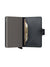 The Secrid Miniwallet Mirum by Secrid, shown open in black, reveals a gold credit card partially inserted in its metallic Cardprotector for RFID/NFC security. It features a right-side button closure and visible edge stitching.