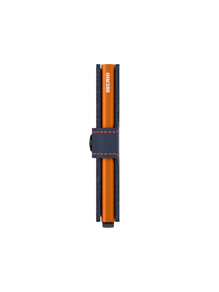 An orange Secrid pen rests in a navy blue Miniwallet Matte Finish Leather holder with orange stitching, positioned vertically against a white background.