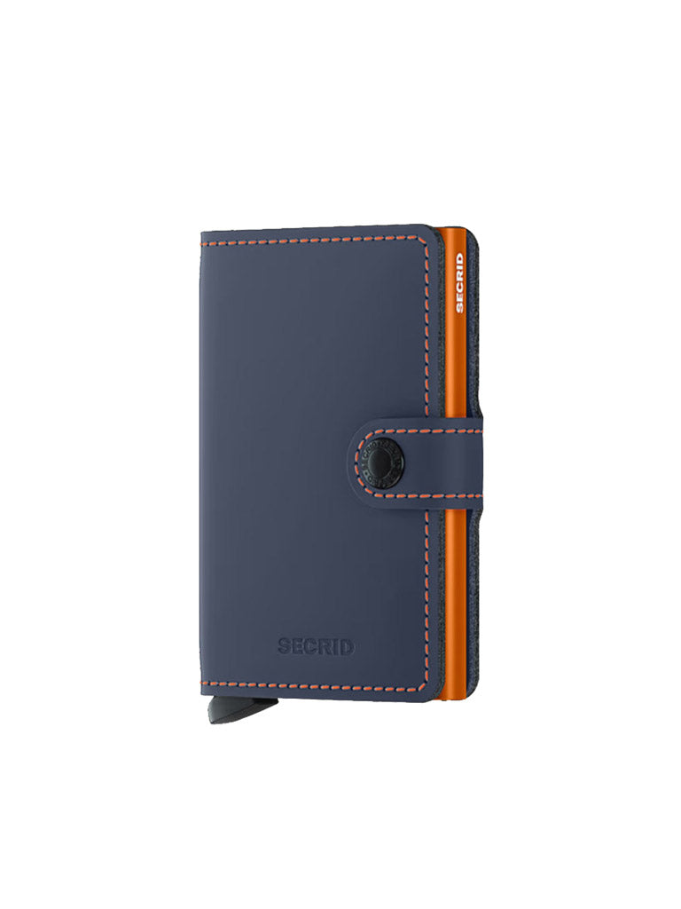 The Secrid Miniwallet Matte Finish Leather features a navy blue exterior with orange stitching, black snap closure, and RFID protection, shown standing upright against a white background.