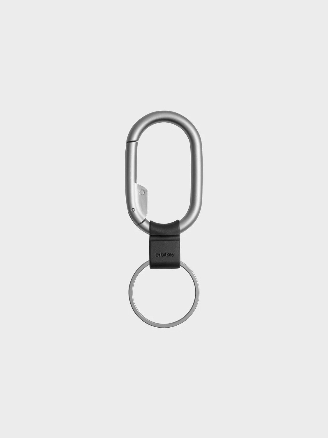 The Orbitkeys Clip Mini Keyring in silver features a minimalist design with a round slim key holder attached by a black connector, shown on a plain light gray background.
